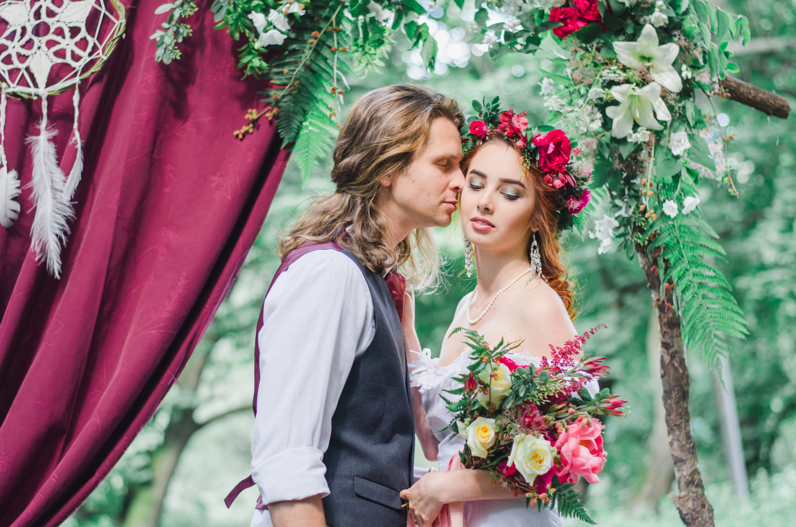 boho couple couple if a forest holding flowers