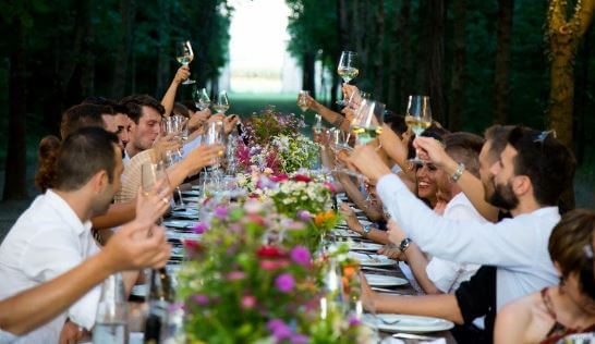 wedding-guests a large long table filled with people and flowers at a wedding ceremony