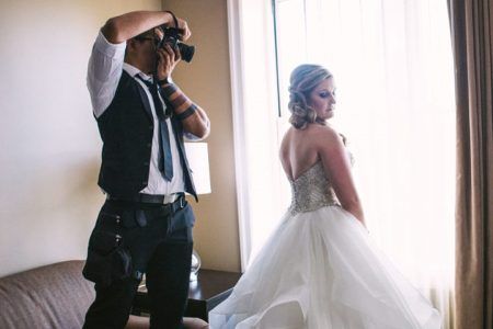 10 Tips for Choosing the Perfect Wedding Photographer _ A Practical Wedding wedding photographier taking photo for bride at window how to choose a wedding photographer