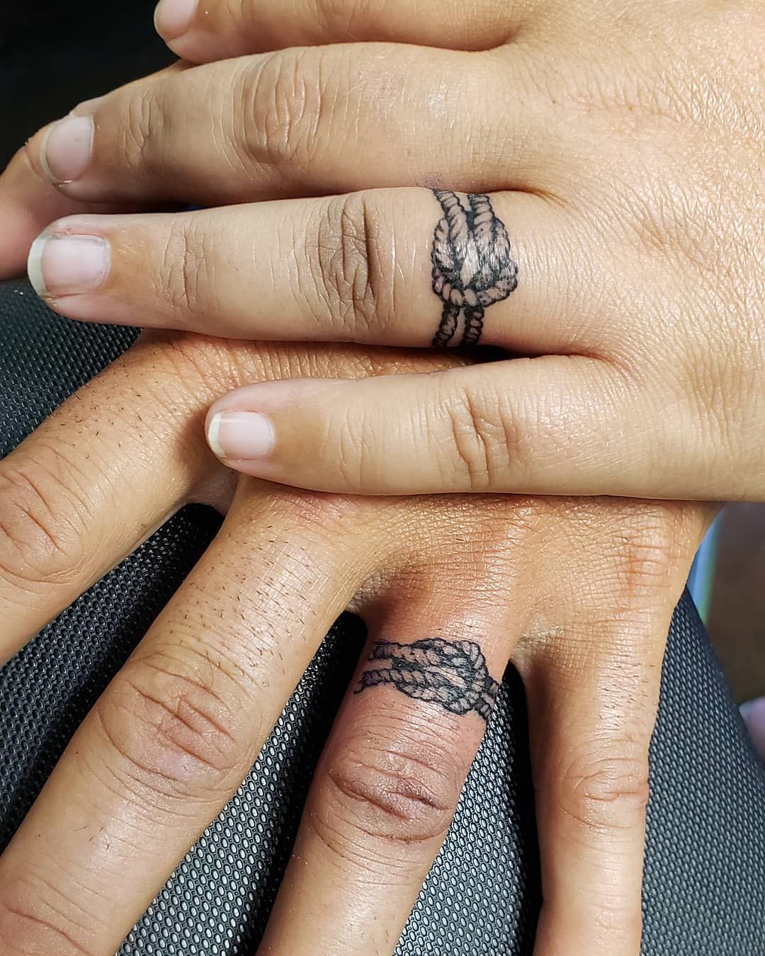 20 Delicate Wedding Ring Tattoo Ideas for the Nontraditional Couple photo of a couples hands on top of each other showing off a wedding ring tattoo