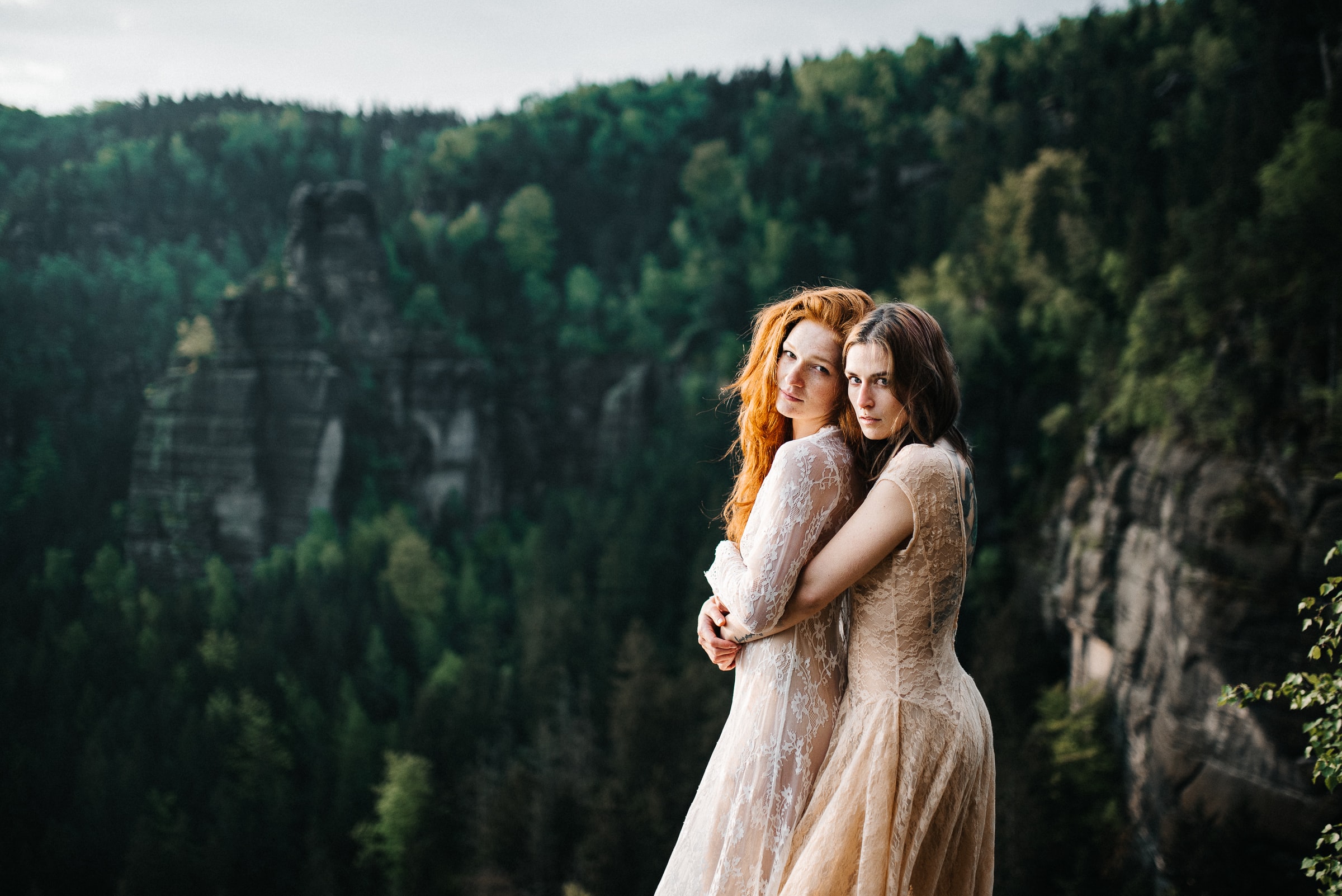 steven-ritzer-kb74nNqmUNw-unsplash 2 young ladies hugging in wedding dresses on a cliff top couples ceremonies with the celebrant angel in aberdeen