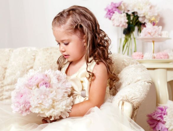 flower girl picture of a flower girl sitting holding a posey type of wedding bouquet with the celebrant angel