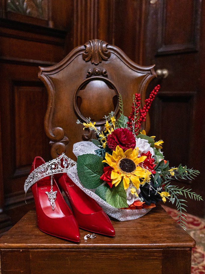 a pair of red wedding shoes alongside a bouquet and a tiara