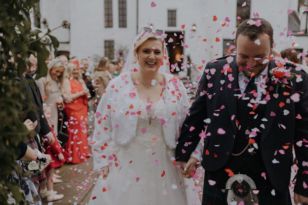 photo of scott and frances onder on their wedding day at maryculter house hotel aberdeen walking through the confetti with the wedding guests, with mary gibson the celebrant angel aberdeen