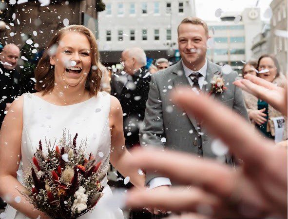 a photo of jen and sean after their wedding ceremony in the confetti shot outside union kirk aberdeen wedding venue with mary gibson the celebrant angel aberdeen
